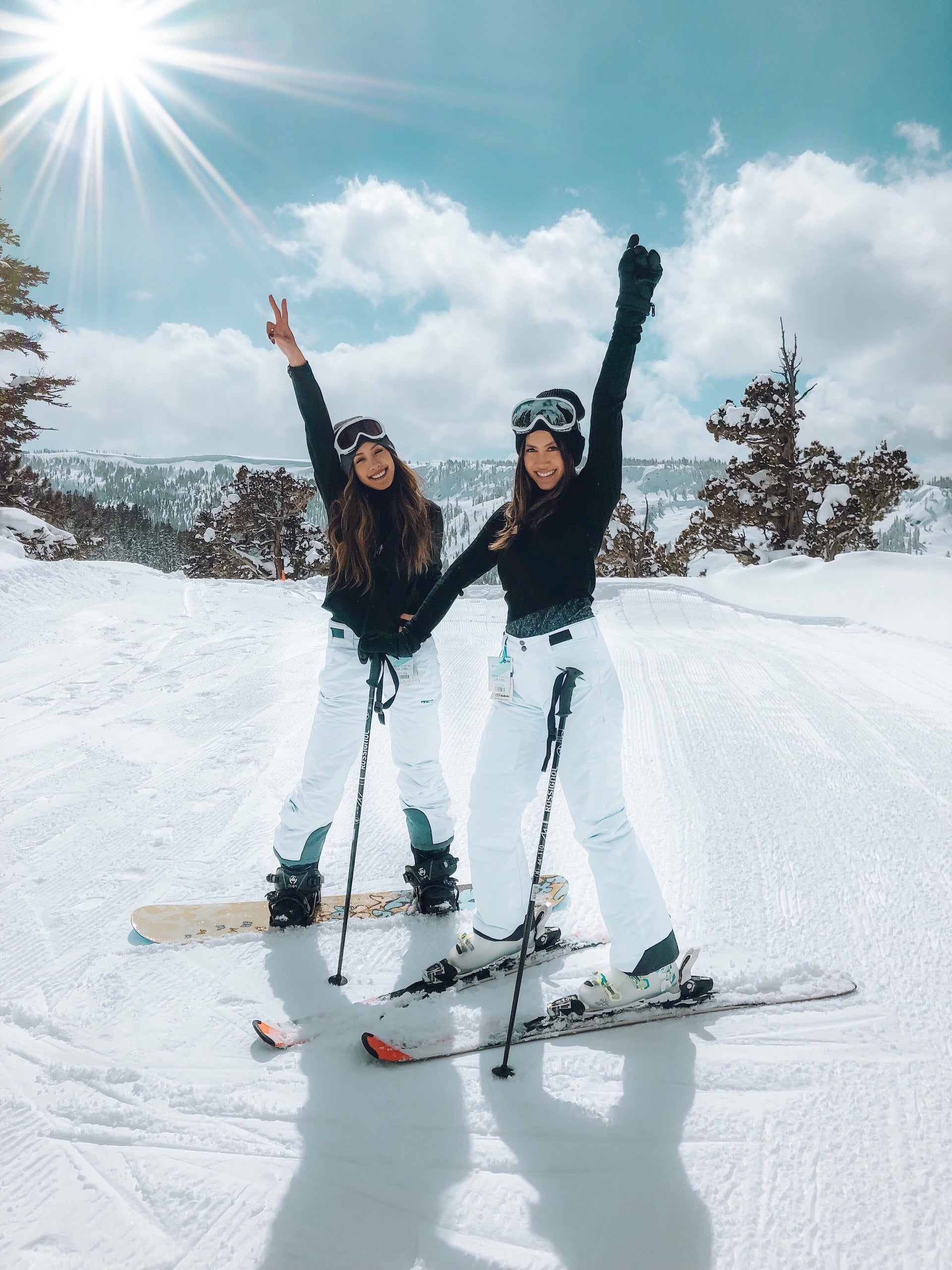 Two women on ski's at the snow with SUNNYBOD refillable sunscreen brush's to protect their skin from UV rays. 